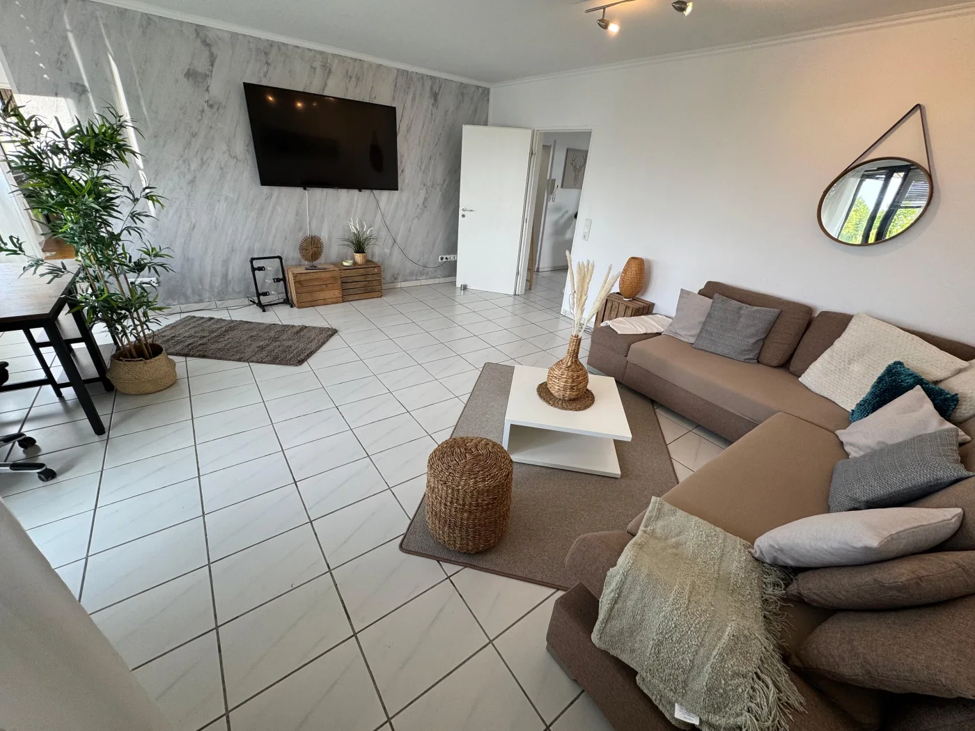 Geräumiges Wohnzimmer einer Monteurwohnung in NRW mit Couch, Fernseher und modernem Interieur