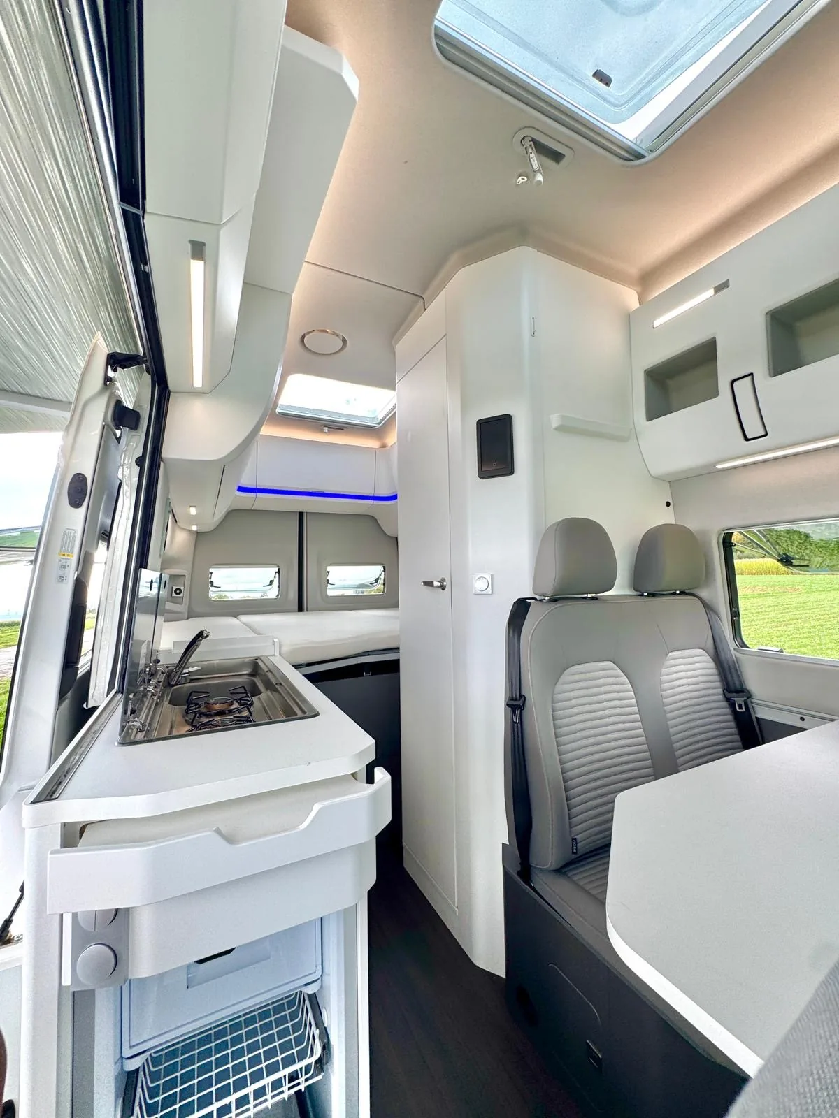 Luxuriöser Wohnbereich des VW Grand California mit moderner Küche und blauem Ambientlicht