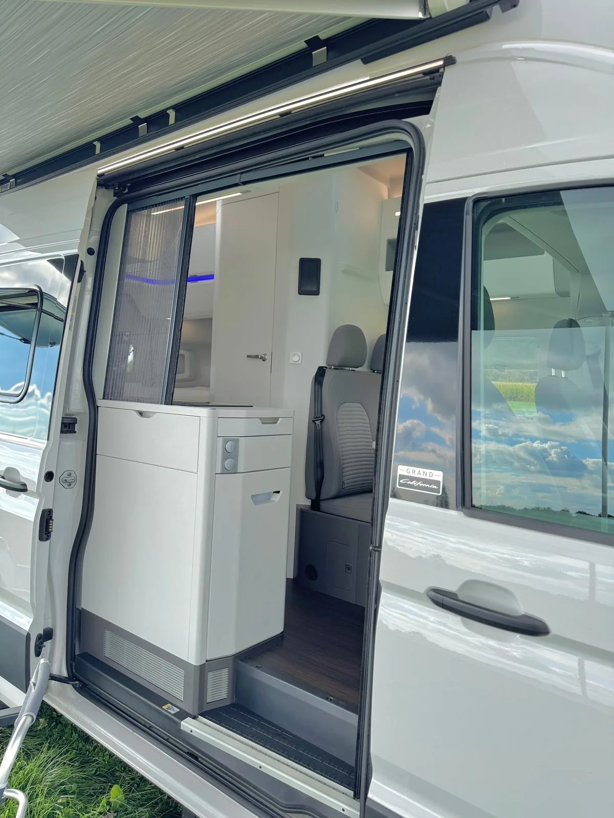 Geöffnete Schiebetür des VW Grand California mit sichtbarem Grand California Emblem