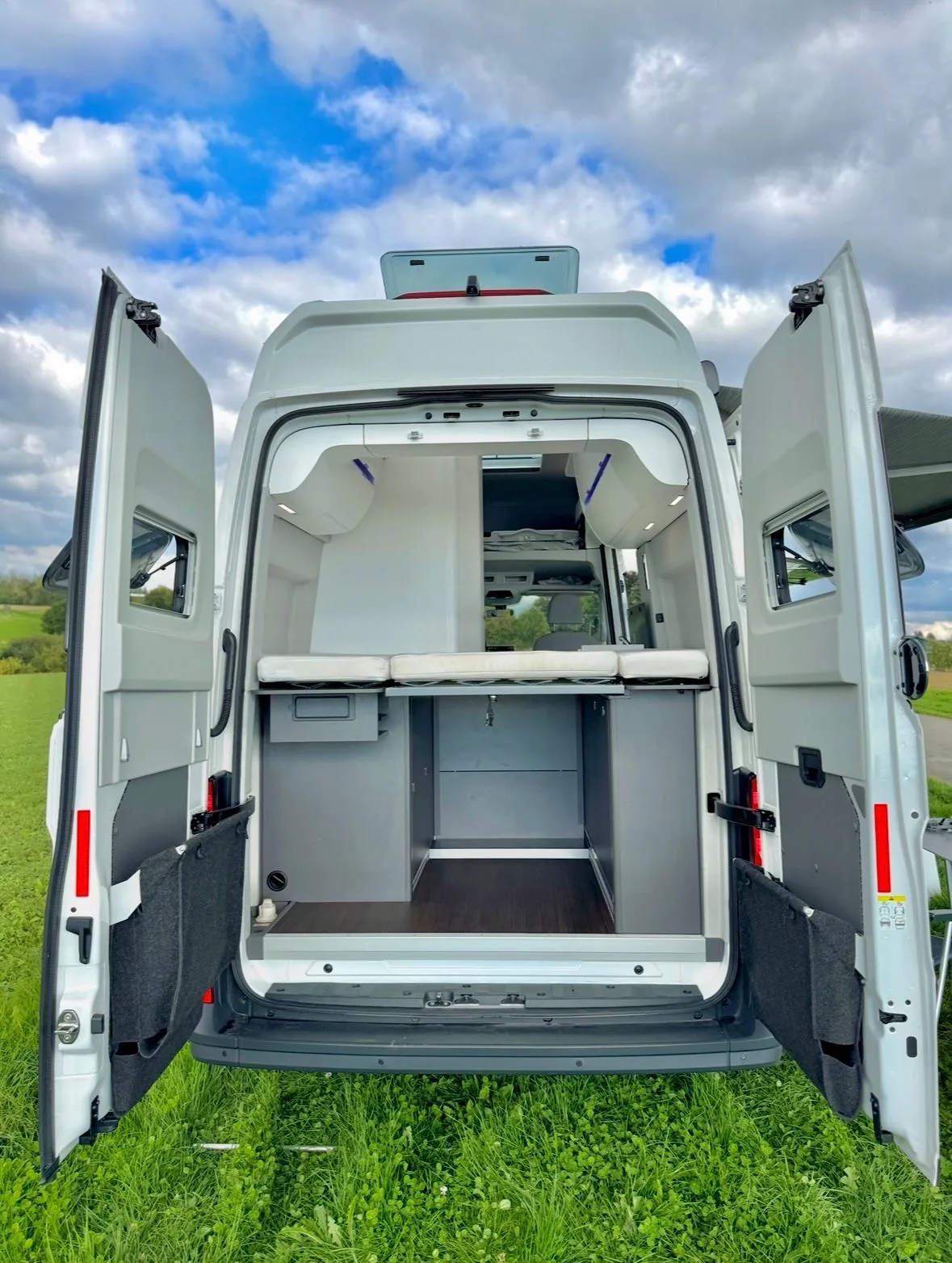 VW Grand California von hinten mit offenen Hecktüren und sichtbarem Vorzelt